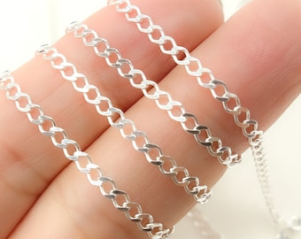 Puede incluir: Primer plano de una delicada cadena de plata con un diseño de eslabones de bordillo. La cadena se muestra sobre un fondo suave, resaltando su superficie brillante y reflectante. Los eslabones están estrechamente conectados, creando un patrón continuo.