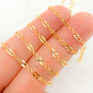 May include: A close-up of five gold chains with a textured, oval-shaped link. The chains are arranged in a fan shape, with the shortest chain at the top and the longest chain at the bottom.