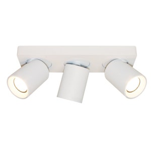 Peut inclure: Un luminaire de plafond blanc avec trois spots orientables. Le luminaire a une base rectangulaire et les spots sont cylindriques.