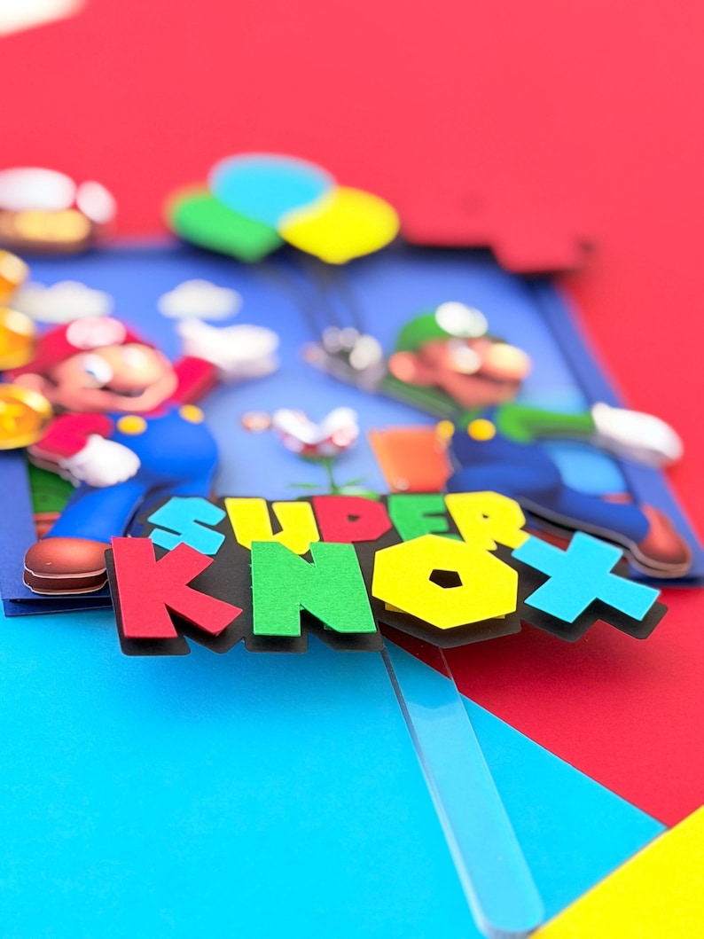 May include: A colorful 3D art piece featuring the text "SUPER KNOX" in bold, multi-colored letters. The artwork depicts cartoon characters Mario and Luigi, with a blue background and red, blue, and yellow accents. The overall theme is video game-related.