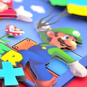 May include: A colorful, layered papercraft featuring the character Luigi from the Super Mario Bros. video game series. Luigi is depicted in his signature green hat and blue overalls, with a blue sky and other game elements.