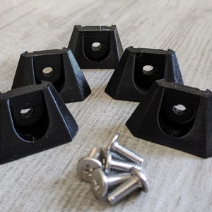 Peut inclure: Cinq supports muraux en plastique noir avec un trou au centre et quatre vis argentées.