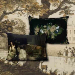 May include: Two decorative throw pillows with black velvet fabric. One pillow features a floral design with white, yellow, and blue flowers. The other pillow features a painting of a woman reclining on a sofa.
