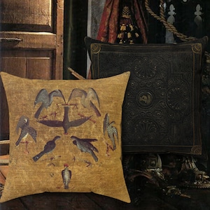 May include: Two decorative throw pillows, one with a black background and intricate gold patterns, and the other with a gold background and a stylized image of birds in a circular pattern.