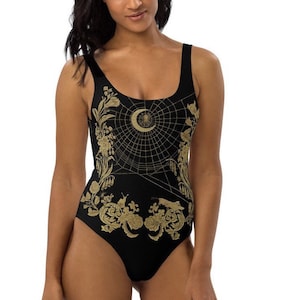 May include: Black one-piece swimsuit with a gold spiderweb design featuring a crescent moon and a spider. The design also includes floral and botanical elements.