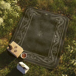 May include: Black and white picnic blanket featuring a spider web design and a border of snakes. The text "Come into my Parlour" is printed on the blanket.