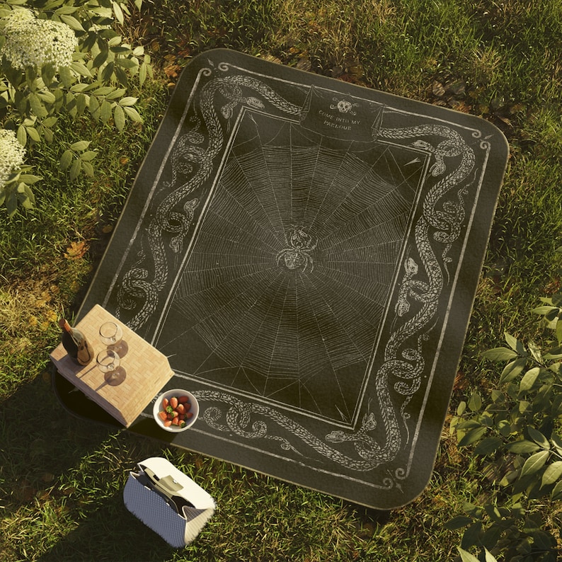 May include: Black and white picnic blanket featuring a spider web design and a border of snakes. The text "Come into my Parlour" is printed on the blanket.