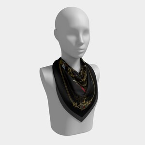 May include: A black silk scarf with a gold and colorful floral pattern. The scarf is tied around the neck of a mannequin.