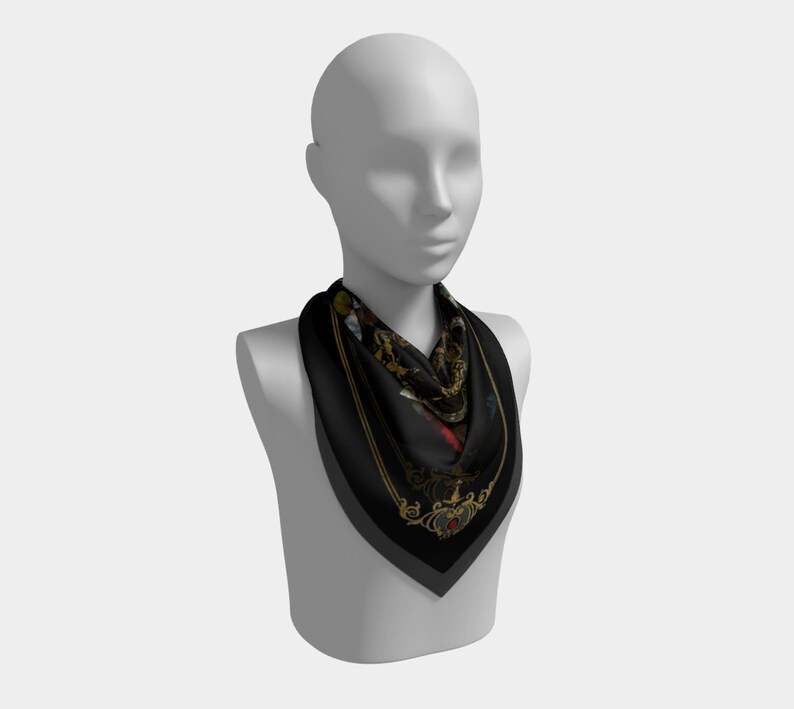 May include: A black silk scarf with a gold and colorful floral pattern. The scarf is tied around the neck of a mannequin.