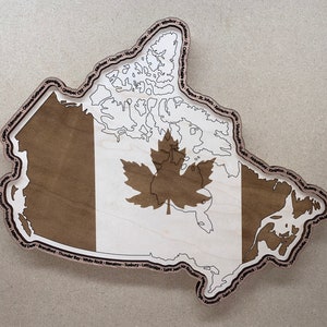 May include: A wooden map of Canada with the Canadian flag in the centre. The map is outlined with the names of major cities in Canada.