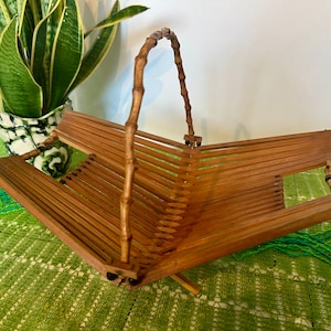 May include: A brown, foldable bamboo basket with a handle. The basket is made of woven bamboo strips and has a natural finish.