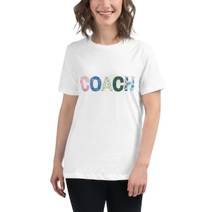 May include: White t-shirt with the word "COACH" printed in colorful patterned letters.
