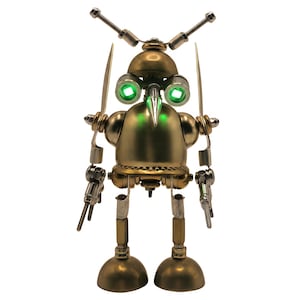 Può includere: Una scultura di robot metallico costruita con componenti hardware color ottone. Presenta due occhi circolari verde brillante, un naso appuntito a forma di becco, due aste simili ad antenne sulla testa e due pale simili a eliche sulle spalle.