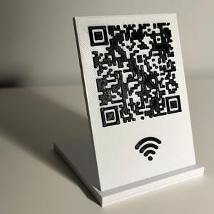 Può includere: Supporto in plastica bianca con un codice QR bianco e nero e un simbolo wifi stampato su di esso.