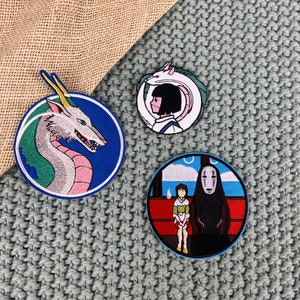 May include: Three embroidered iron-on patches featuring characters from the animated film Spirited Away. The patches are circular and feature a white dragon, a young girl with a white spirit, and a masked spirit.