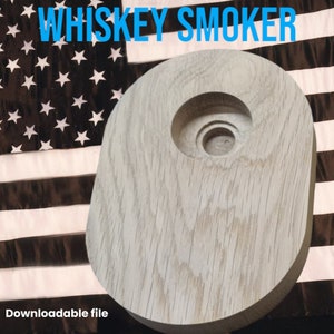Op de afbeelding: Een houten whiskey roker met een uitgesneden centrale kamer. De tekst "WHISKEY SMOKER" wordt in het blauw boven de roker weergegeven. De achtergrond toont de Amerikaanse vlag. De woorden "Downloadable file" staan onderaan.