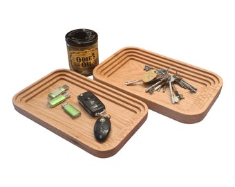 Peut inclure: Deux plateaux en bois aux bords arrondis, l'un avec un porte-clés et l'autre avec une clé de voiture et des clés USB. Les plateaux sont en bois brun clair et ont une finition naturelle.