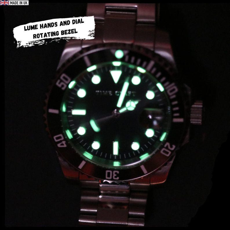 May include: A close-up of a stainless steel watch with a black dial and a rotating bezel. The watch features luminous hands and markers, with the text "LUME HANDS AND DIAL ROTATING BEZEL" in a white box. The watch is marked "MADE IN UK".