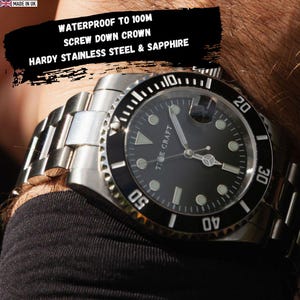 May include: A stainless steel watch with a black face and a black rotating bezel. The watch has a silver band and the text "Tide Craft" is visible on the watch face. The watch is waterproof to 100m.