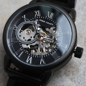May include: A black automatic wristwatch with a skeleton dial and Roman numeral hour markers. The watch face says "Time Craft".