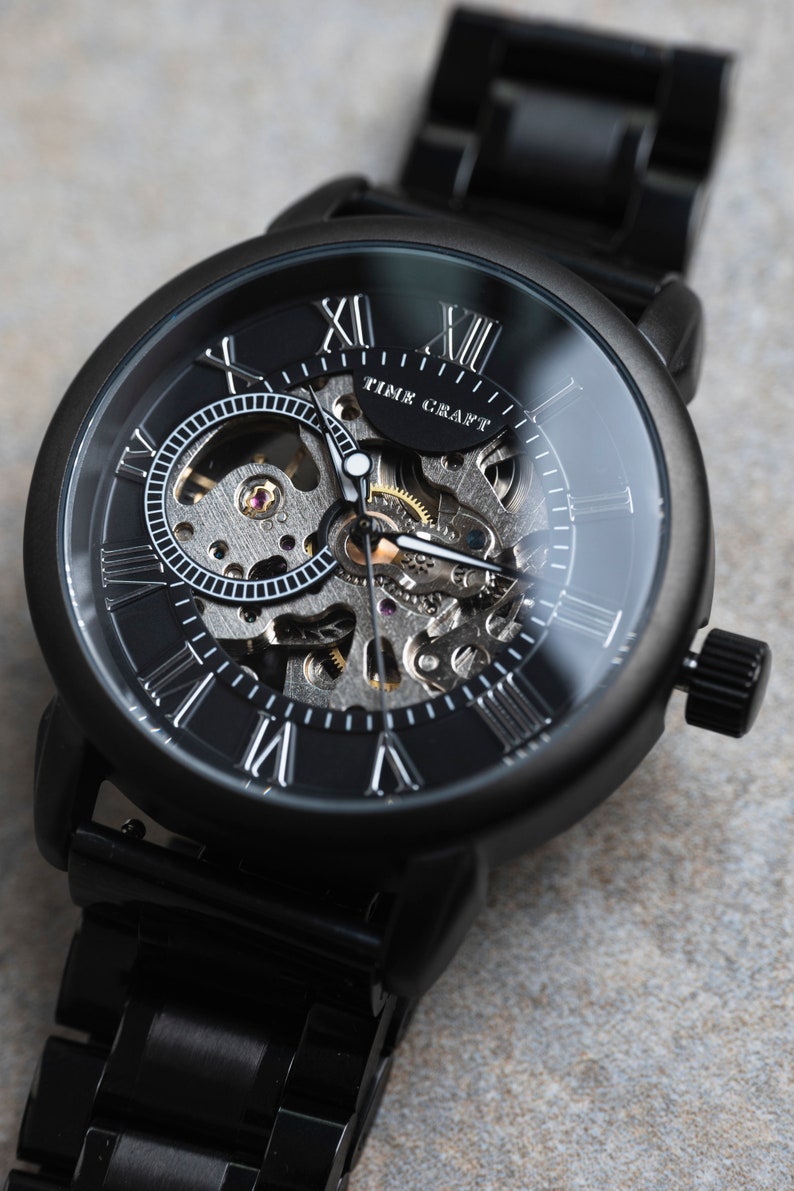 May include: A black automatic wristwatch with a skeleton dial and Roman numeral hour markers. The watch face says "Time Craft".