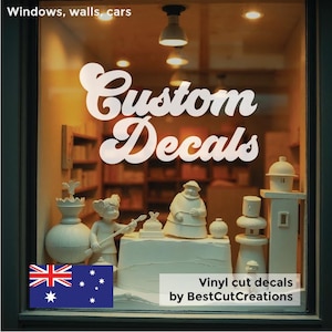 May include: White vinyl decal with the text "Custom Decals" in a retro font style. The decal is displayed on a shop window with a variety of decorative items. The text "Vinyl cut decals by BestCutCreations" is also visible at the bottom of the image.
