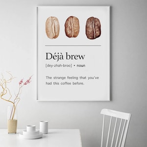 May include: A white poster with a black and white graphic design. The poster features three coffee beans and the text "D&eacute;j&agrave; brew [dey-zhah-broo] &bull; noun The strange feeling that you've had this coffee before."