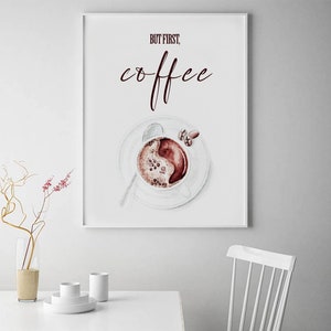 May include: A white poster with the text "But first, coffee" in maroon lettering. A watercolor illustration of a cup of coffee with coffee beans on a white saucer is below the text.