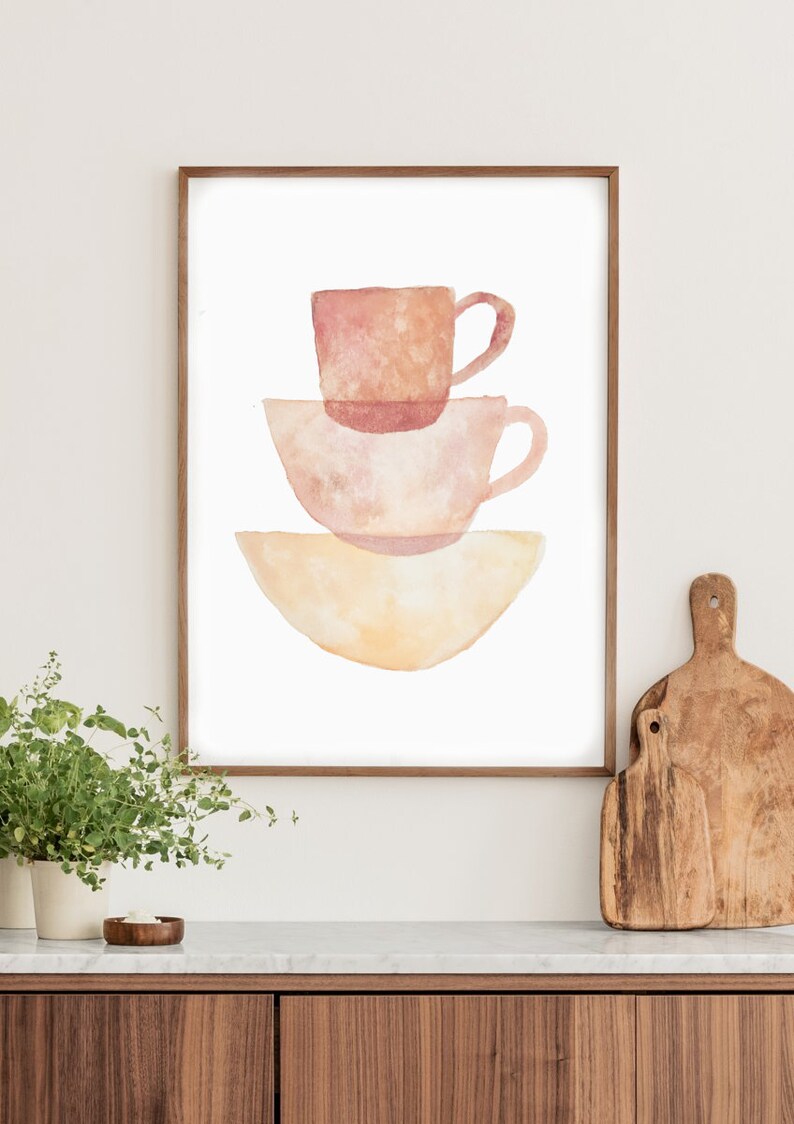 May include: A watercolor painting of three stacked cups in shades of pink and yellow. The cups are arranged in a simple, modern style.