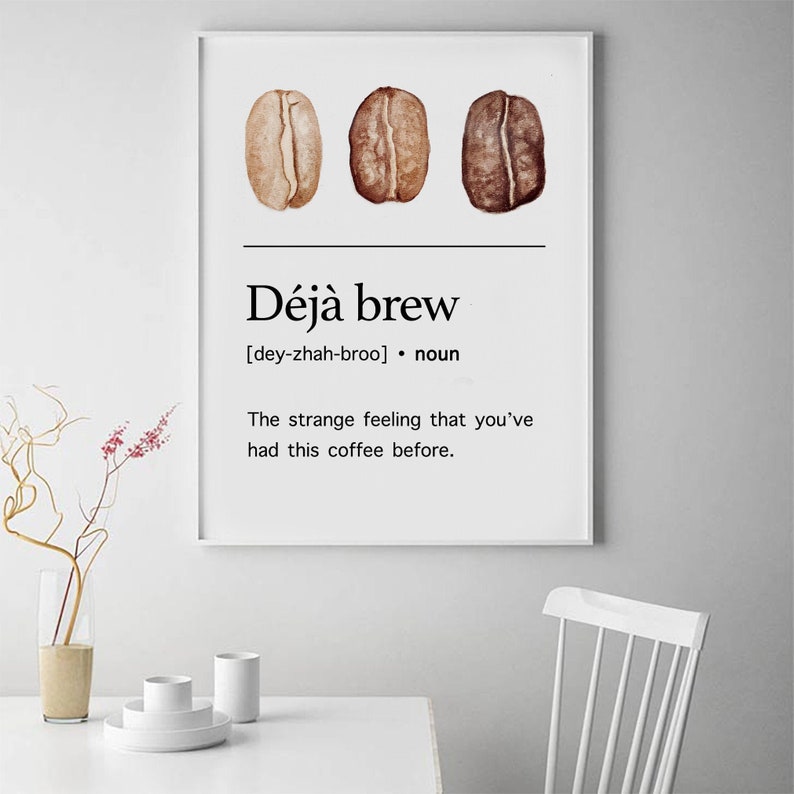 May include: A white poster with a black and white graphic design. The poster features three coffee beans and the text "D&eacute;j&agrave; brew [dey-zhah-broo] &bull; noun The strange feeling that you've had this coffee before."