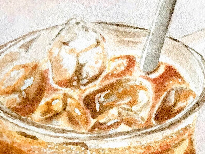 May include: A close-up of a glass of iced coffee with ice cubes and a straw. The coffee is a light brown color and the ice cubes are clear.