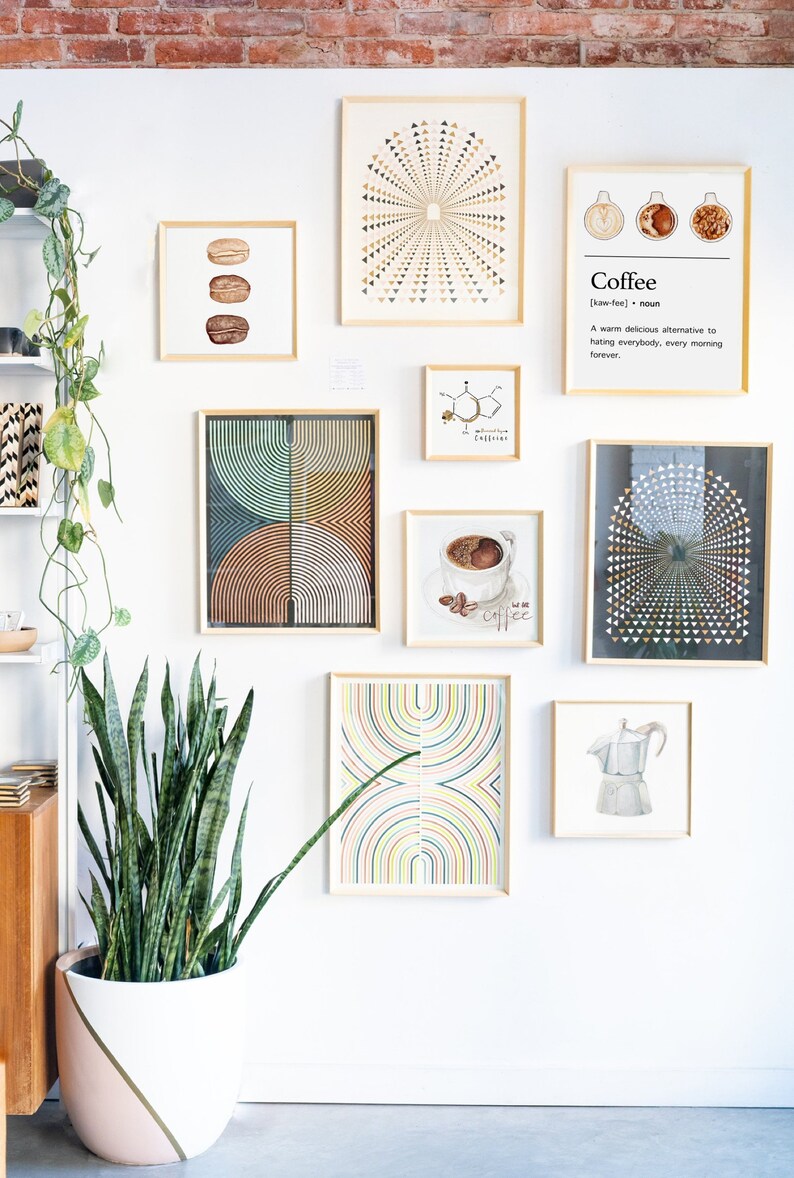 May include: A white wall with a collection of framed art prints. The prints feature geometric patterns, abstract designs, and illustrations of coffee beans and a coffee pot. A potted snake plant sits in front of the wall.