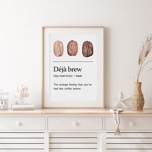 May include: A white framed print with a coffee bean illustration and the text "D&eacute;j&agrave; brew [dey-zhah-broo] noun The strange feeling that you've had this coffee before."