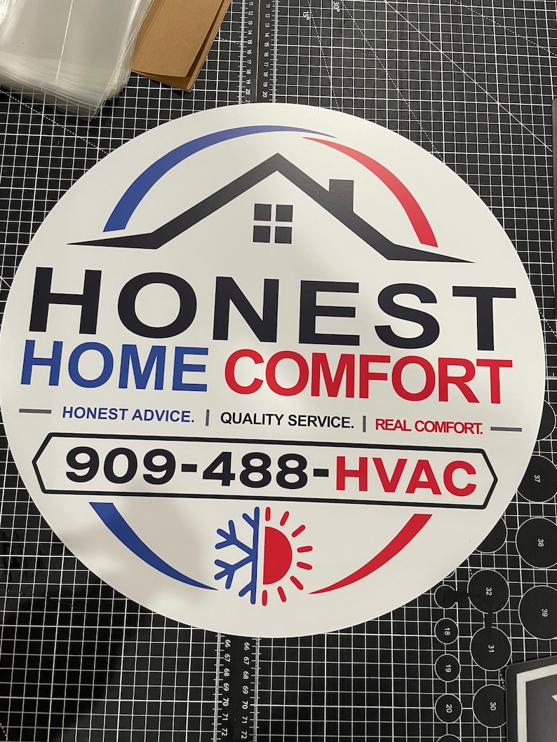 May include: A circular white sign featuring a black house icon, the text HONEST HOME COMFORT, and the slogan HONEST ADVICE. | QUALITY SERVICE. | REAL COMFORT. It includes the phone number 909-488-HVAC and a blue and red snowflake and sun graphic.