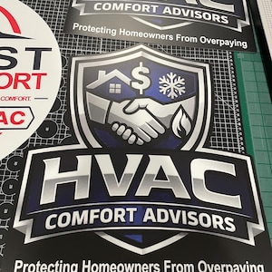 May include: A rectangular sign featuring a shield logo with a handshake, a house, a dollar sign, and a snowflake icon. The text reads HVAC COMFORT ADVISORS and Protecting Homeowners From Overpaying in bold white and silver lettering on a dark blue background.