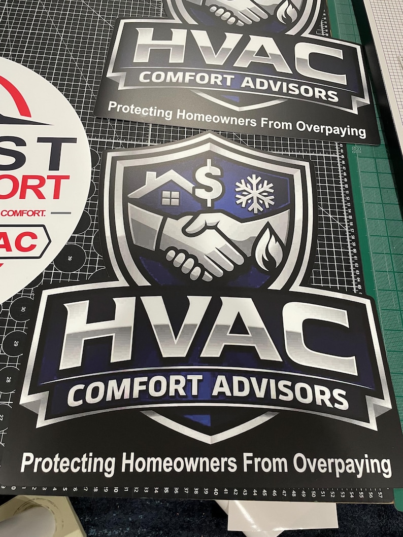 May include: A rectangular sign featuring a shield logo with a handshake, a house, a dollar sign, and a snowflake icon. The text reads HVAC COMFORT ADVISORS and Protecting Homeowners From Overpaying in bold white and silver lettering on a dark blue background.