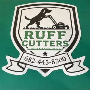 May include: A shield-shaped decal featuring a black silhouette of a dog pushing a lawnmower above the green text RUFF CUTTERS. Below the text is a white banner containing the black phone number 682-445-8300 and a small black star.