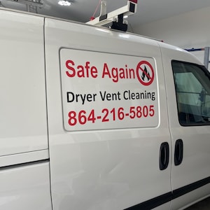 May include: A white commercial van featuring a rectangular sign on the side panel. The sign displays the red and black text Safe Again, the words Dryer Vent Cleaning in black, a red no-fire symbol, and the phone number 864-216-5805 in red.