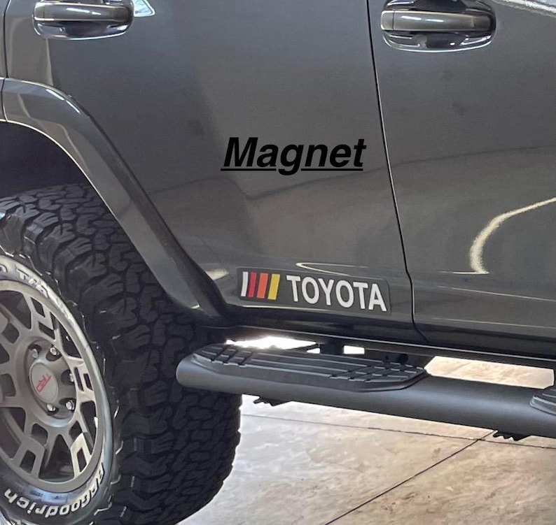 May include: A gray Toyota SUV with a black "Magnet" decal and a red, yellow, and white stripe decal with the word "TOYOTA" on the side.
