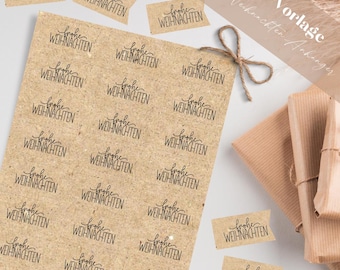 Puede incluir: Una hoja de papel marrón con un patrón repetido de la frase "Frohe Weihnachten" en escritura negra. La hoja está cortada en etiquetas de regalo individuales. La imagen también muestra algunas de las etiquetas ya cortadas y apiladas unas sobre otras.