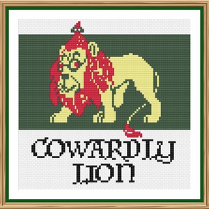 Könnte beinhalten: Ein Kreuzstichmuster mit einem Comic-Löwen, der einen roten Hut und eine Brille trägt. Der Löwe steht auf grünem Hintergrund und der Text "COWARDLY LION" befindet sich unter dem Löwen.