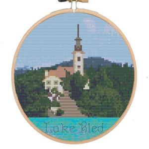 Può includere: Ricamo a punto croce del lago di Bled in Slovenia, con una chiesa su un'isola circondata da un bosco e il testo "Lake Bled".