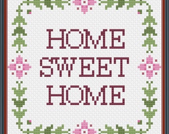 Op de afbeelding: Borduurpatroon met een witte achtergrond en een bordeauxrode rand. Het patroon bevat de woorden "Home Sweet Home" in bordeauxrood met een groene bladrand en roze bloemen.