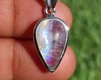 May include: A teardrop-shaped pendant with a silver setting and a rainbow moonstone gemstone.
