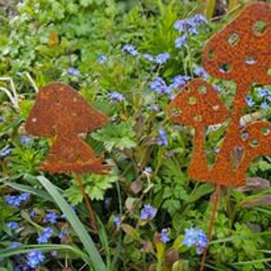May include: Three rusty metal mushroom garden stakes with a whimsical design. The mushrooms are different sizes and have a textured surface.
