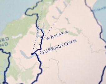 Könnte beinhalten: Nahaufnahme einer Karte, die die Lage von Wanaka und Queenstown in Neuseeland zeigt. Die Karte ist mit einer blauen Linie und einer gepunkteten Linie markiert.