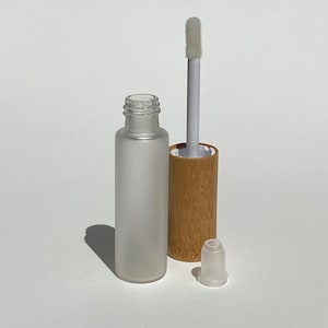 May include: A frosted glass bottle with a bamboo lid and a white applicator wand. The bottle is empty and the wand is capped with a clear plastic tip.