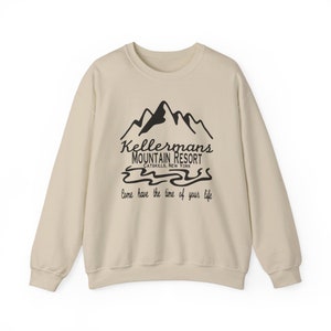 Könnte beinhalten: Cremefarbenes Sweatshirt mit schwarzer Grafik eines Bergmassivs, dem Text "Kellermans Mountain Resort Catskills, New York" und dem Satz "Come have the time of your life". Das Sweatshirt hat einen Rundhalsausschnitt und lange Ärmel.