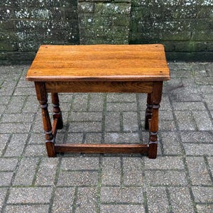 May include: A white ceramic mug with a black handle and the text "But First, Coffee" in a black, bold font. The mug is on a white surface. The mug appears to be approximately 355 ml.