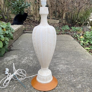 May include: White ceramic table lamp with a textured design and a brown base. The lamp has a white cord and a white plug.